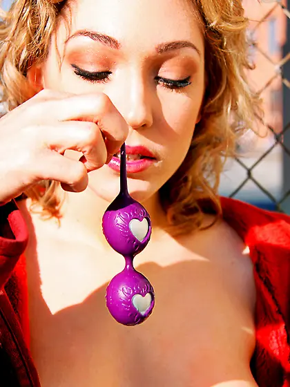 Lily Luvs in long red coat plays with purple vagina balls in pub