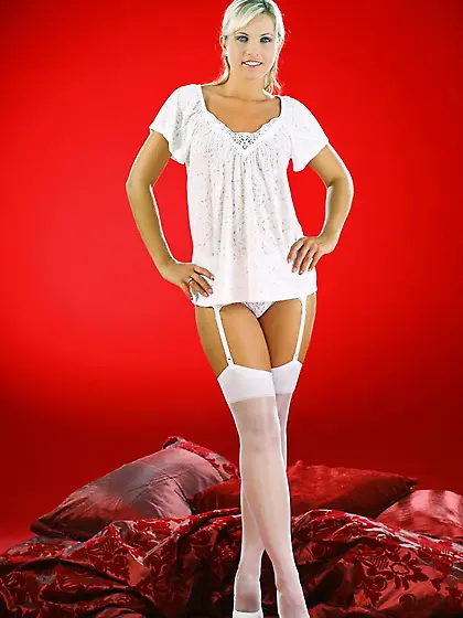 Jenni wearing all white relaxes on her bed.