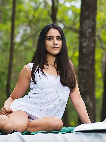 Dark-haired beauty with exotic features posing on a bed,  in the