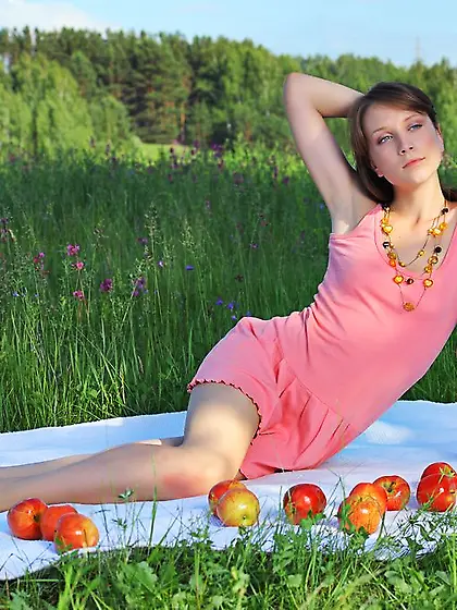 Dark-haired chick poses naked while surrounded by lots of apples