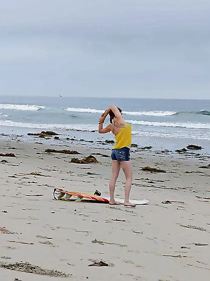 Redhead colleen in swimsuit is playfully posing with surfboard o