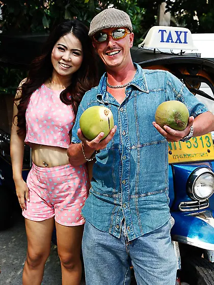 Man in flat cap and sunglasses asks Thai lovely with curly hair