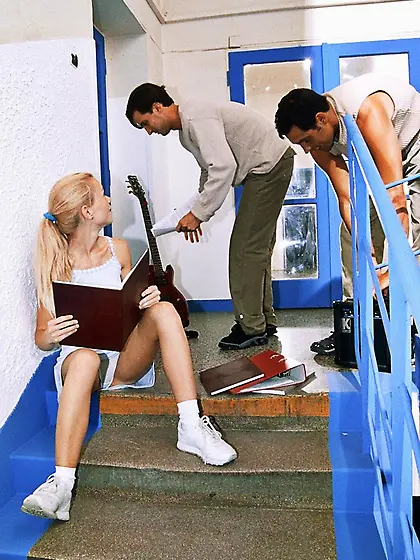 College girl is sitting on the stairs when two teachers offer to