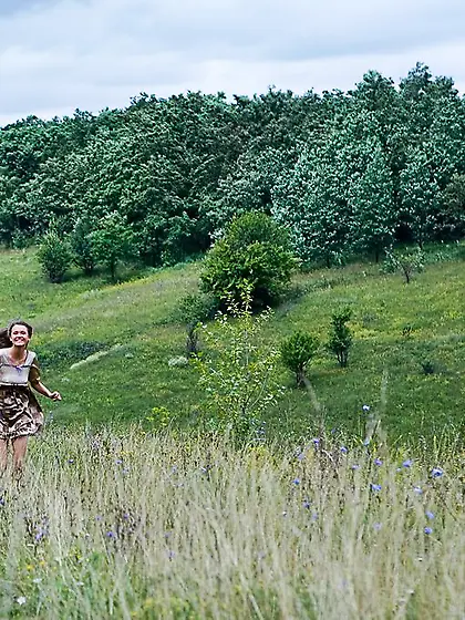 Cheerful brunette posing completely naked in the middle of a fie