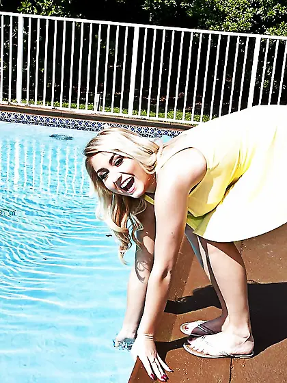 Playful blonde walks around swimming pool and shows her perfect