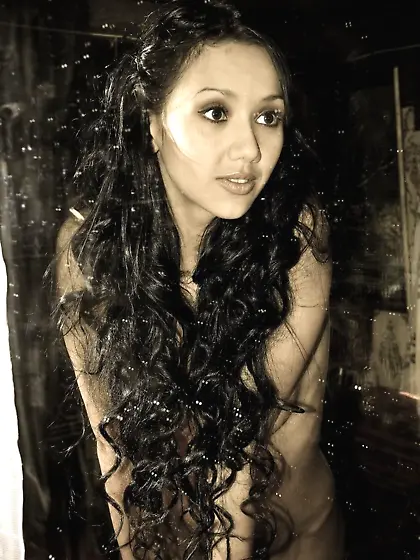 Tanned brunette eating an apple while posing naked in the countr