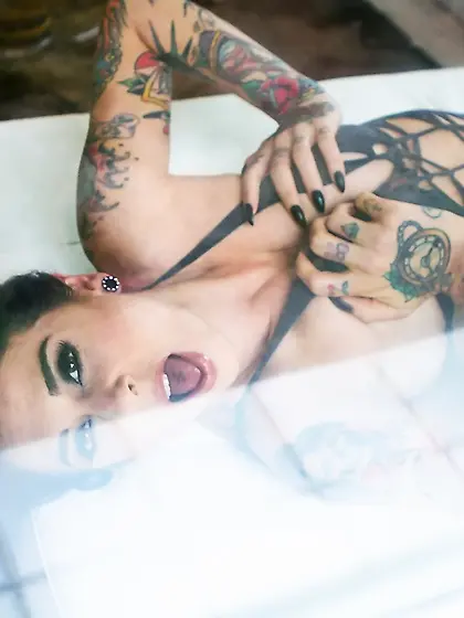 Porn queen strips in front of the glass door and continues posin