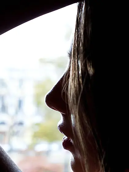 Young Foxi Di is standing on her knees on leather armchair and o