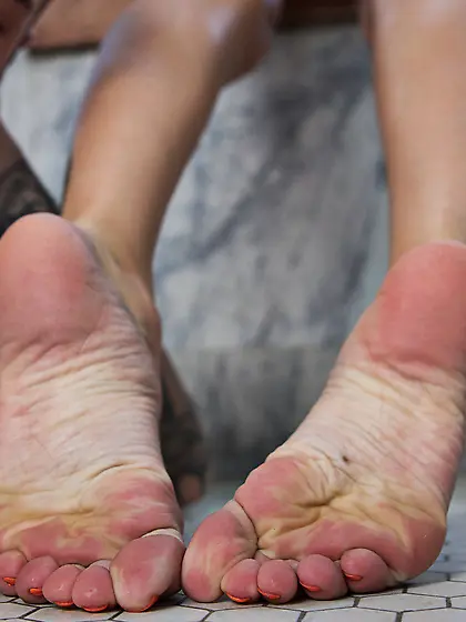 Inked naked stunner with big tits uses her lovely feet to stroke