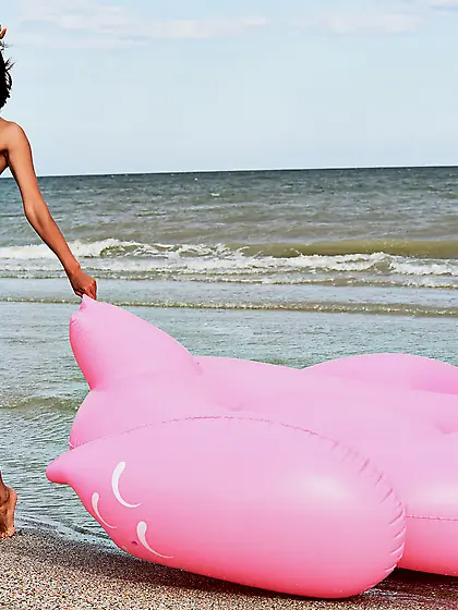Short-haired brunette with a great tan poses next to inflatable