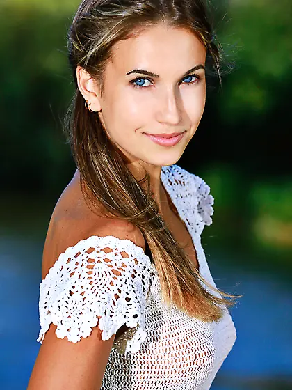 Denim shorts wearing blue-eyed brunette goddess poses next to a