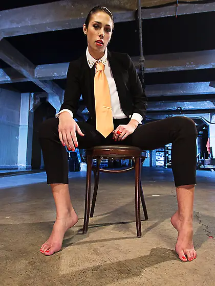 Elegant babe in a business suit demonstrates her sexy feet in a