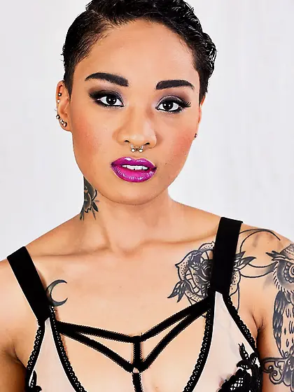 Tattooed oriental love with purple lipstick looks into the camer