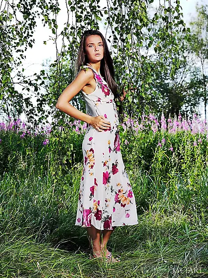 Long-haired brunette in a flowery dress shows her goodies outdoo