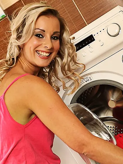 Smiling blonde with wavy hair posing naked on the bathroom floor