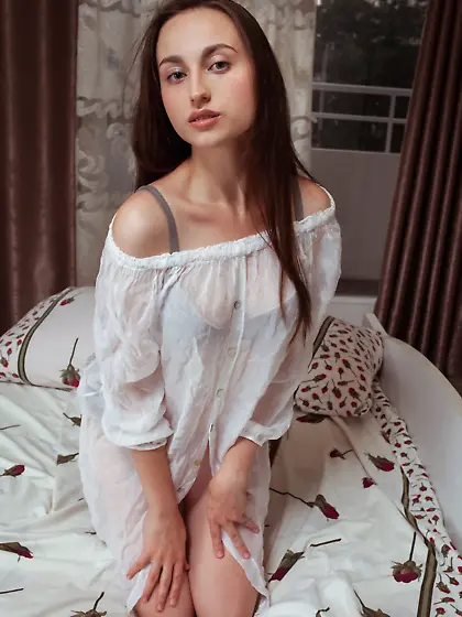 Long-haired brunette in grey lingerie strips naked on a big bed