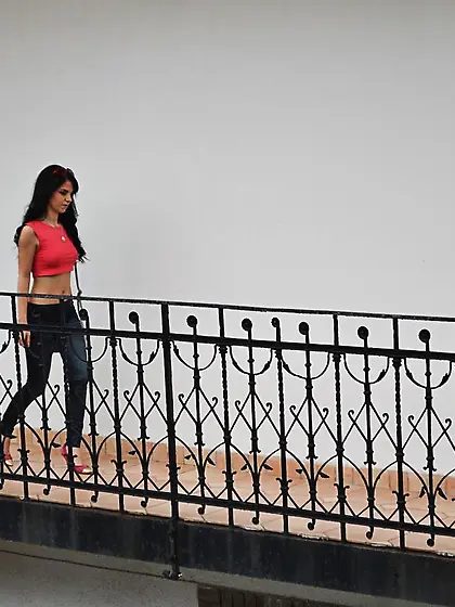 Babe with red sunglasses in hair wears blue jeans that she pulls