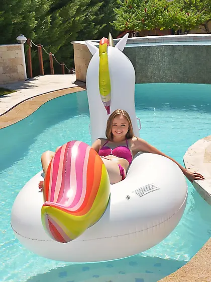 Female is lying on inflatable unicorn in pool and then makes man
