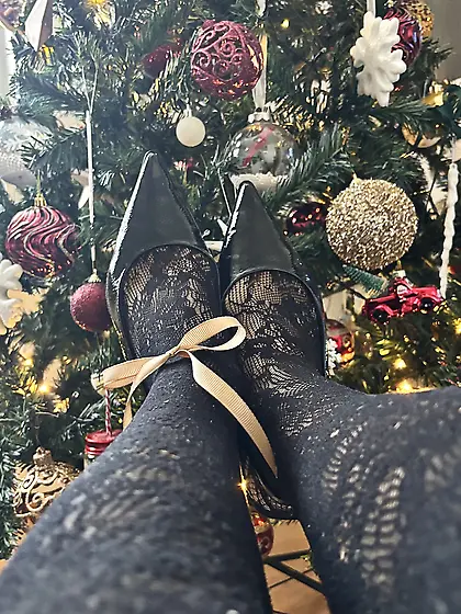 Feet in heels and stockings under a christmas three