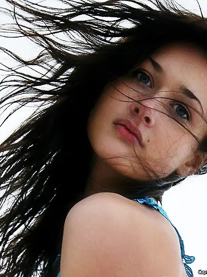 The wind is playing with her long hair and she is playing naked