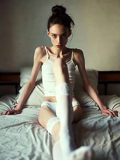 Skinny anorexic brunette girl on bed