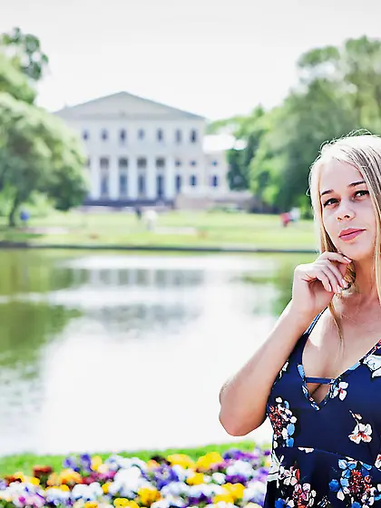 Blue dress blonde teen poses next to a luxurious country mansion