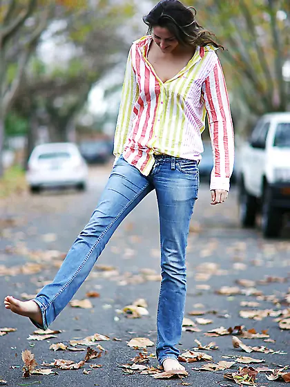 Teen in striped shirt and jeans walks the streets and strips on