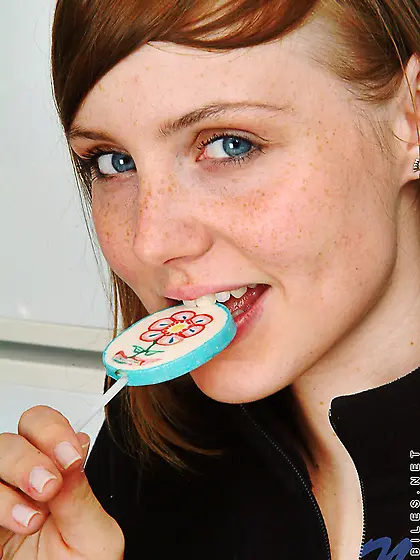 Adorable ginger model licks a candy in the kitchen and takes off